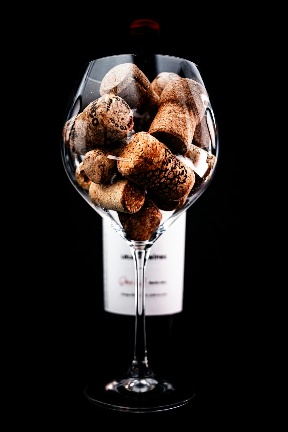 a wine glass filled with wine corks on top of a table