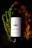 A bottle of red wine labeled 'Leleka wines' is positioned against a dark background. The label includes a simple black and white design with minimalist line art. Surrounding the bottle are fresh green rosemary sprigs on the left and dried autumn leaves on the right, adding a natural and seasonal touch to the composition.