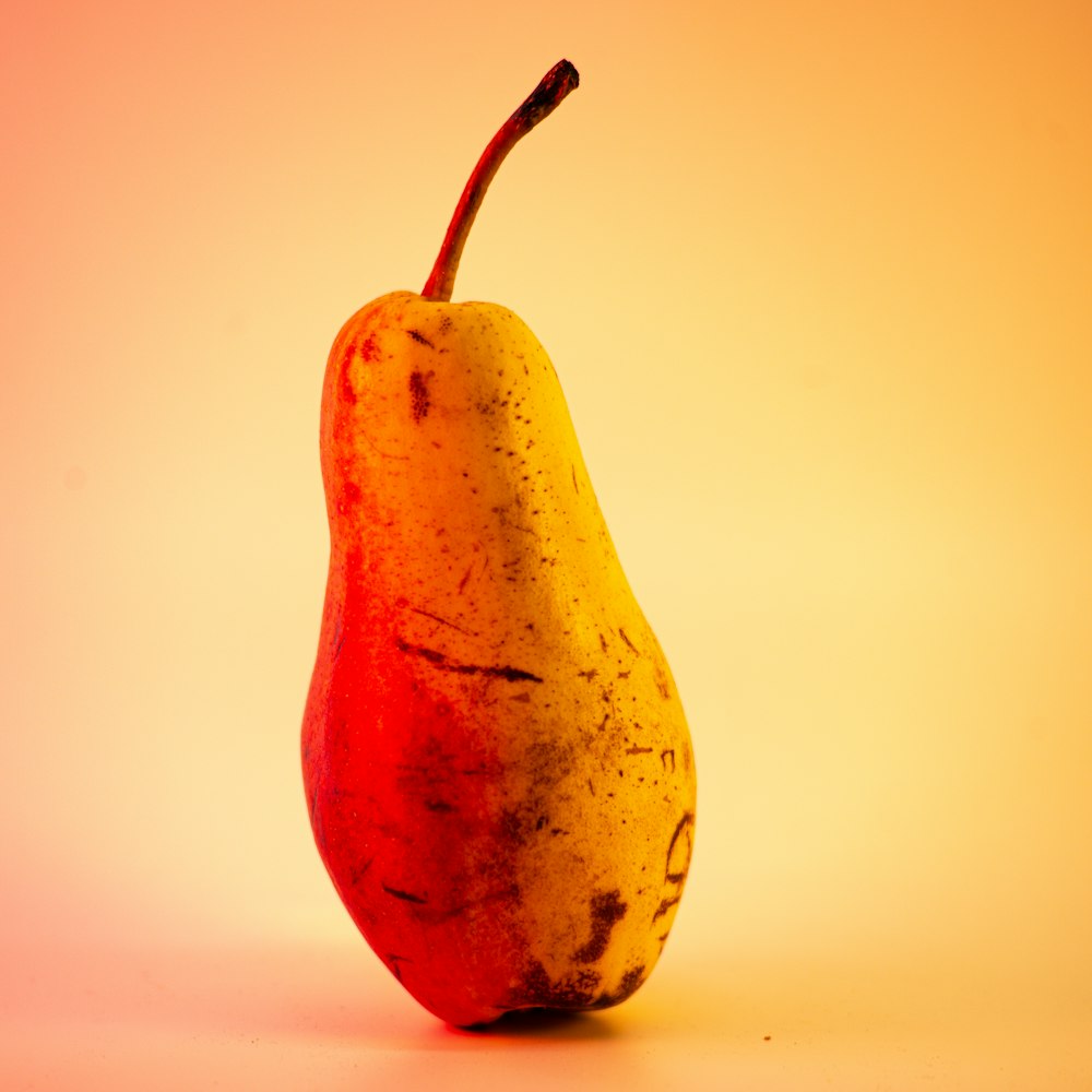 a yellow and red pear sitting on top of a table