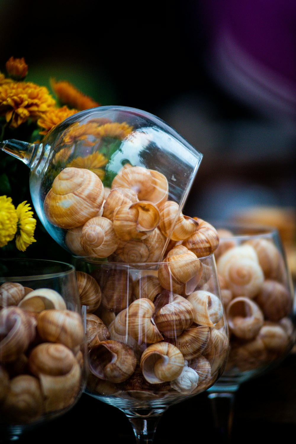 a glass bowl filled with nuts next to a vase filled with flowers