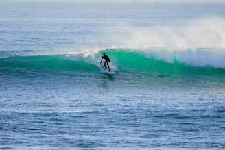 Close-up of a surfer riding a crystal-clear wave, water droplets sparkling in the sunlight.