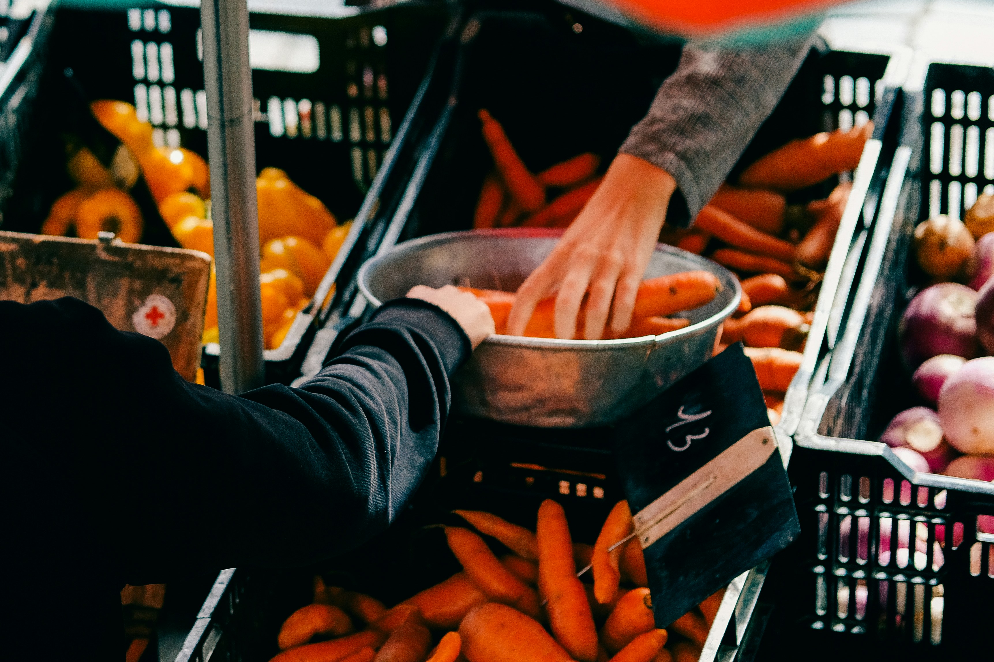 a person reaching for carrots in a basket