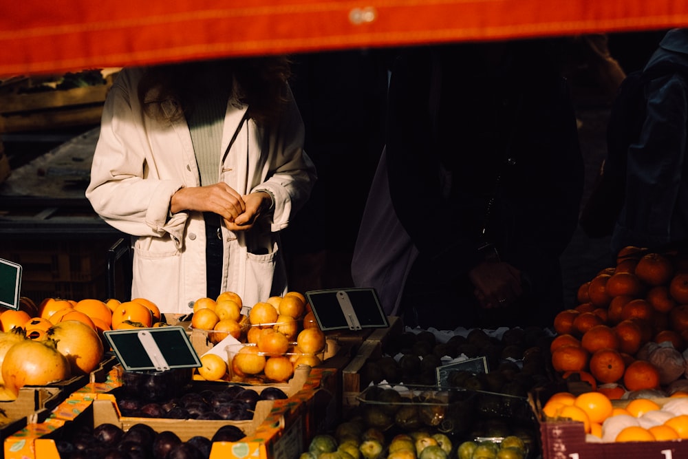 una donna in piedi davanti a un banco di frutta