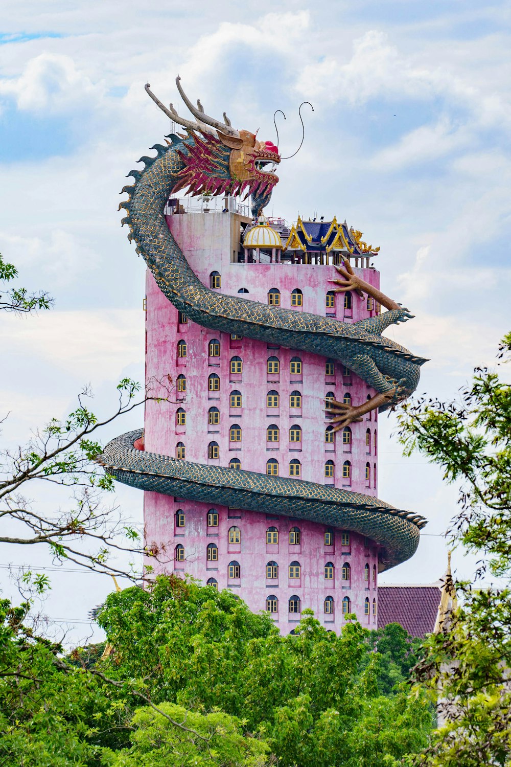 a tall pink building with a dragon on top of it