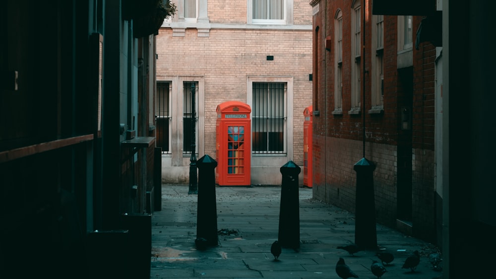a red phone booth in a narrow alley way
