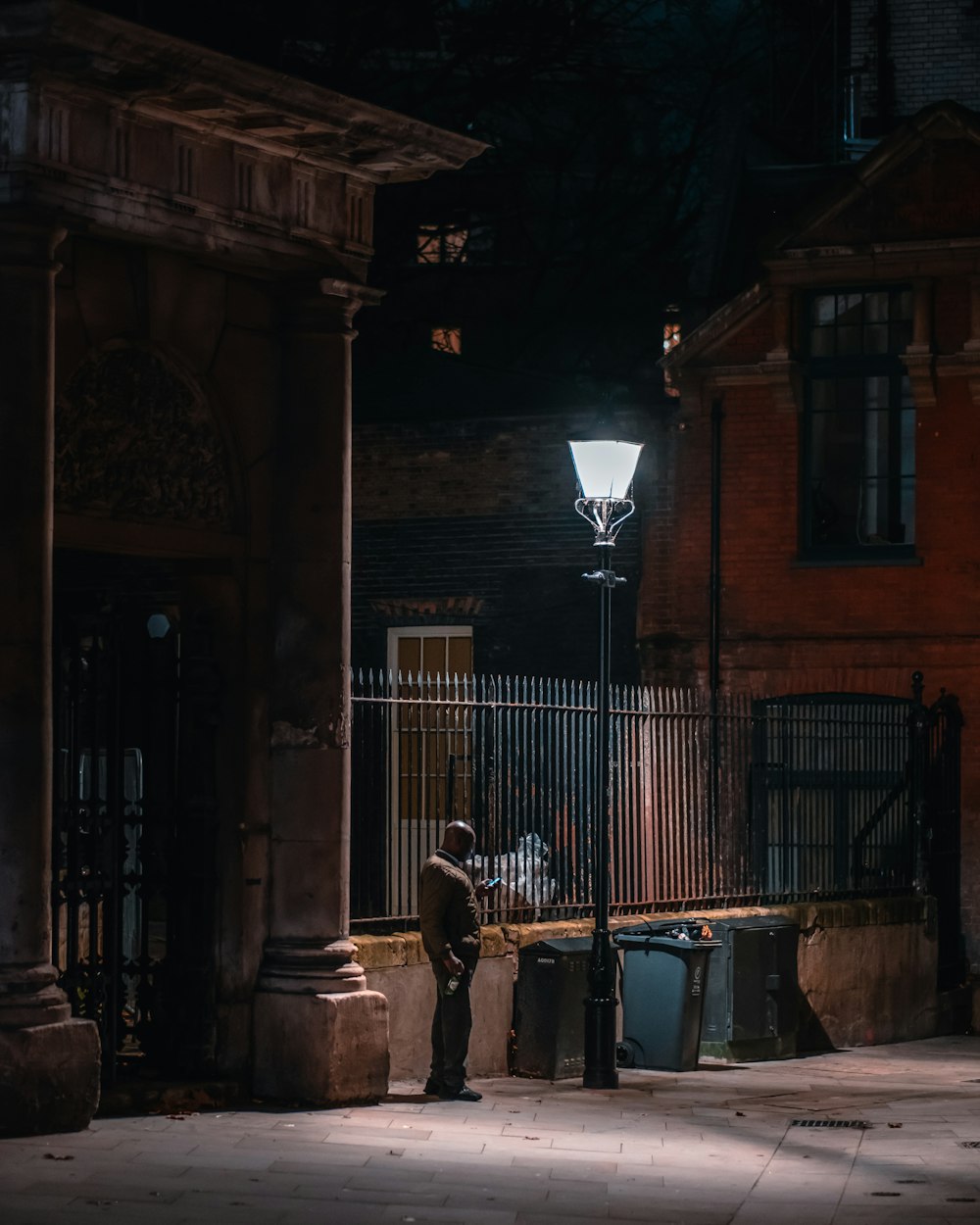 a man standing on a sidewalk next to a street light