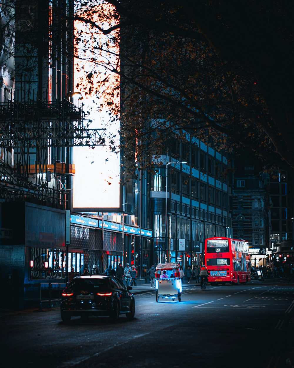 a red double decker bus driving down a city street