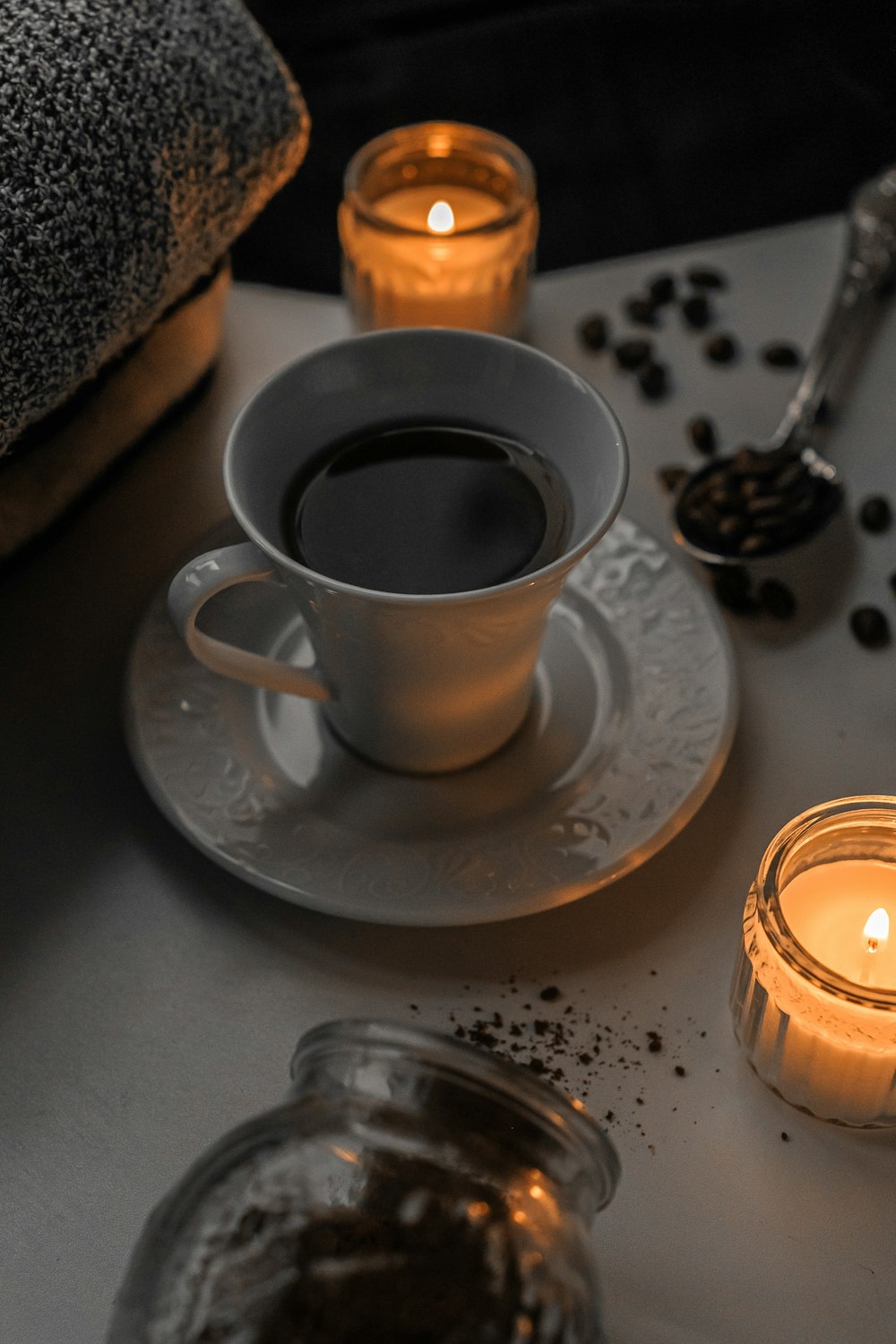 a cup of coffee sitting on top of a table next to a candle