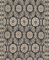 Intricate floral and geometric patterns in symmetrical arrangements dominate the textile design. Cream-colored motifs stand out against a dark background, forming a network of stylized flowers and ornate shapes. The design is bordered by a repetitive pattern of similar motifs.