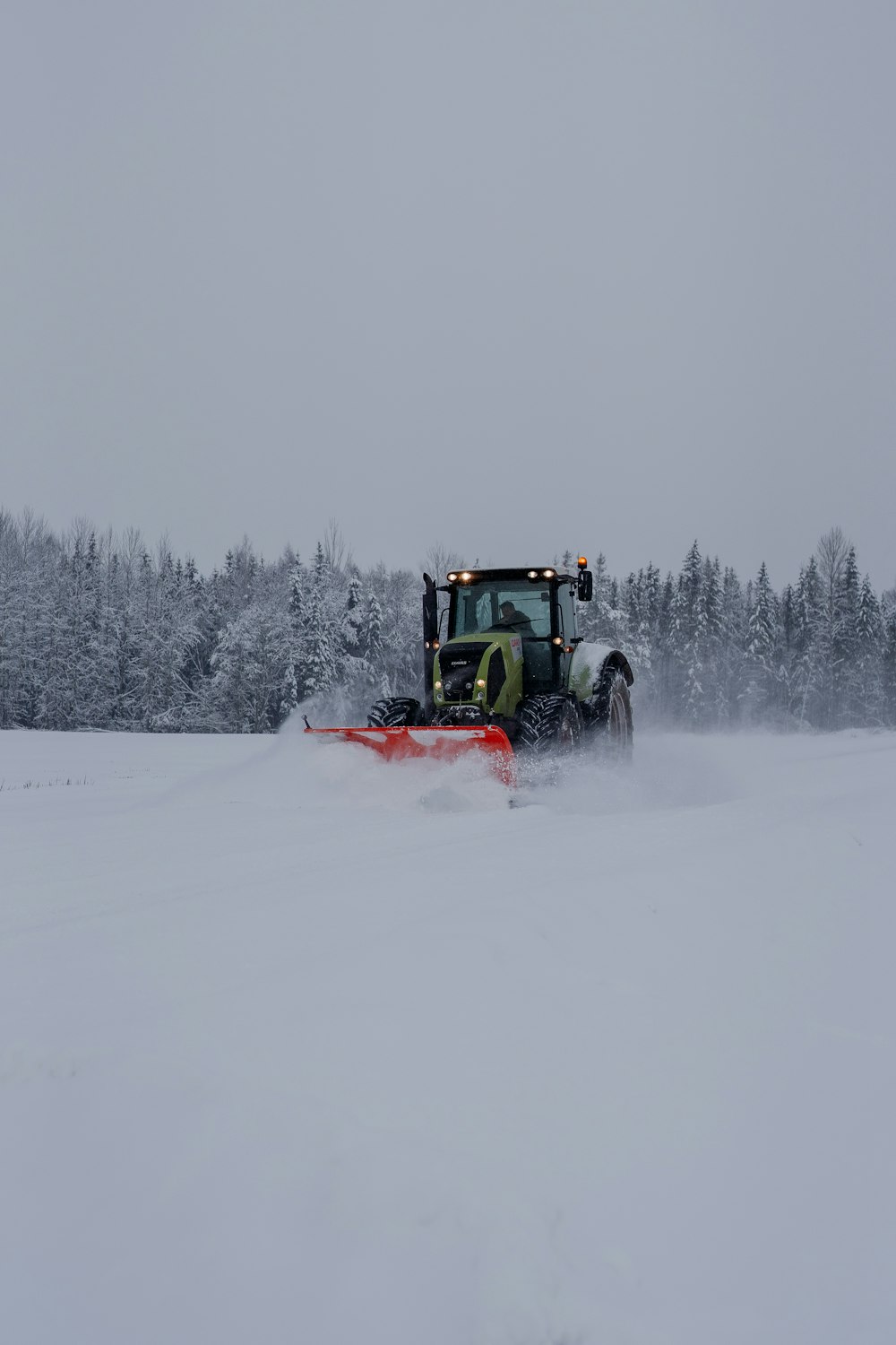 a tractor plows through a snow covered field