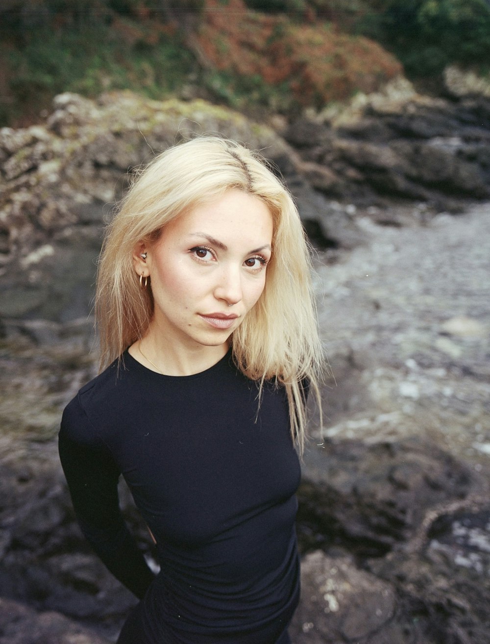 a woman with blonde hair standing in front of a river