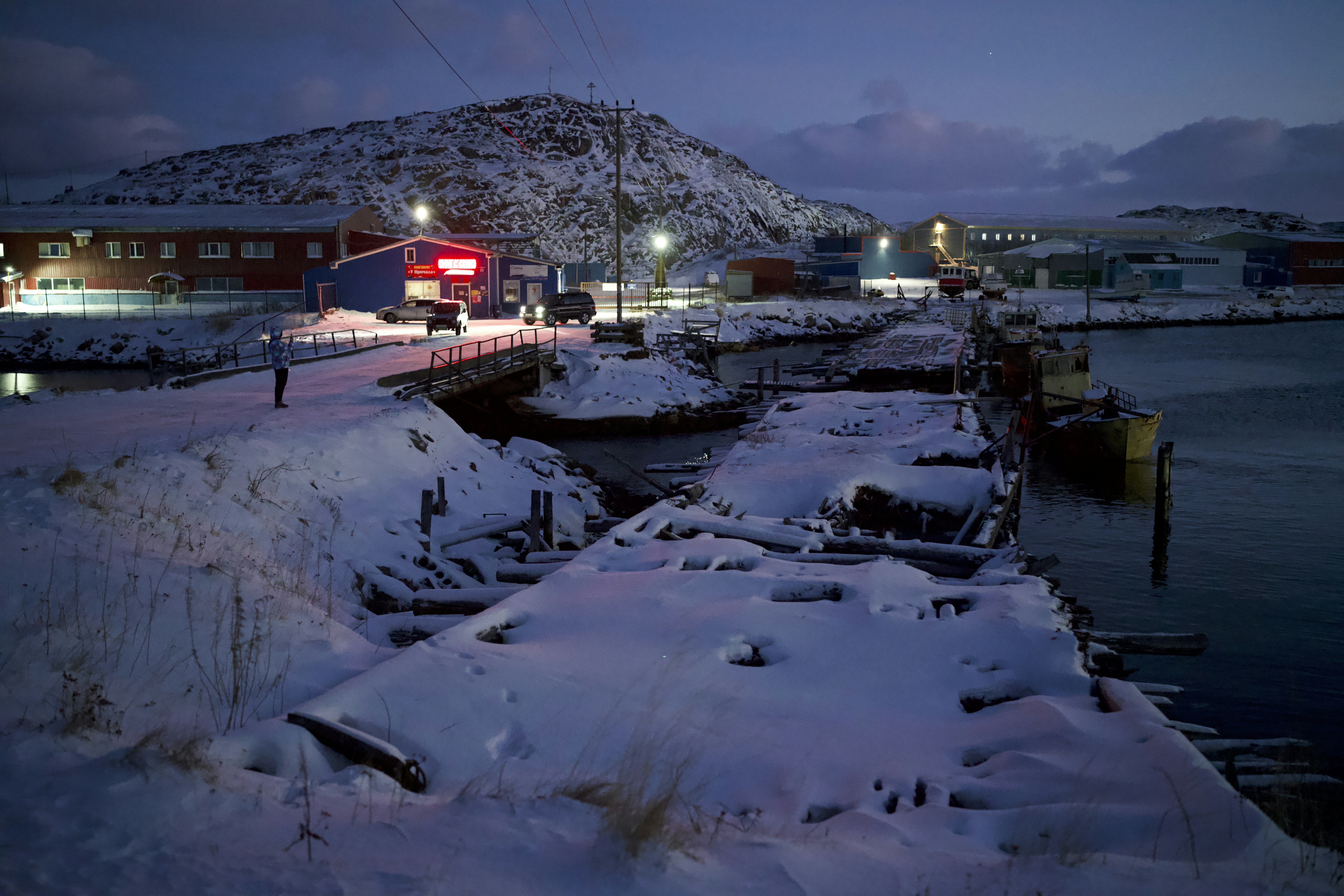 a snow covered pier with a red building in the background