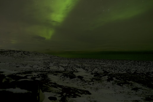 A serene Icelandic landscape under shimmering northern lights with ancient runes carved into nearby stones.