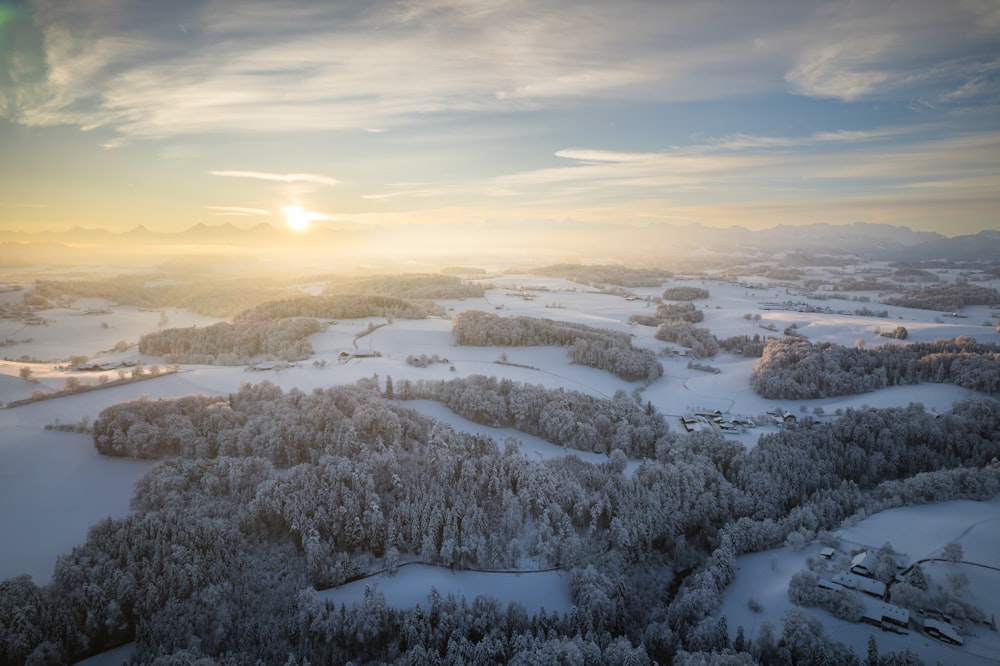 the sun is setting over a snowy landscape