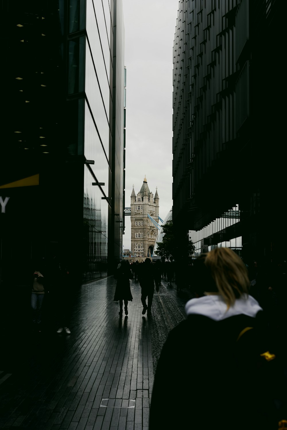 a group of people walking down a street next to tall buildings