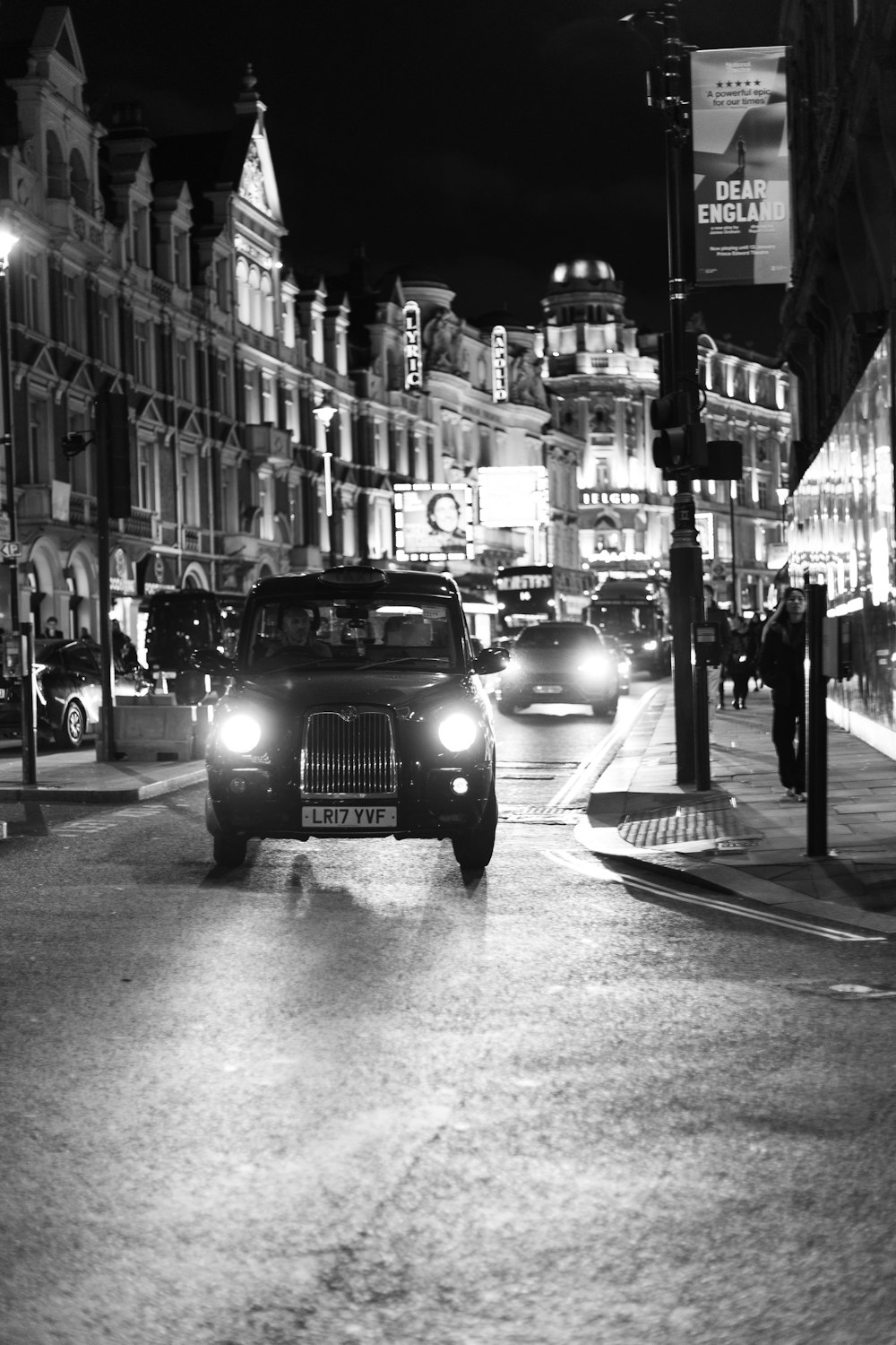 a black and white photo of a city street at night