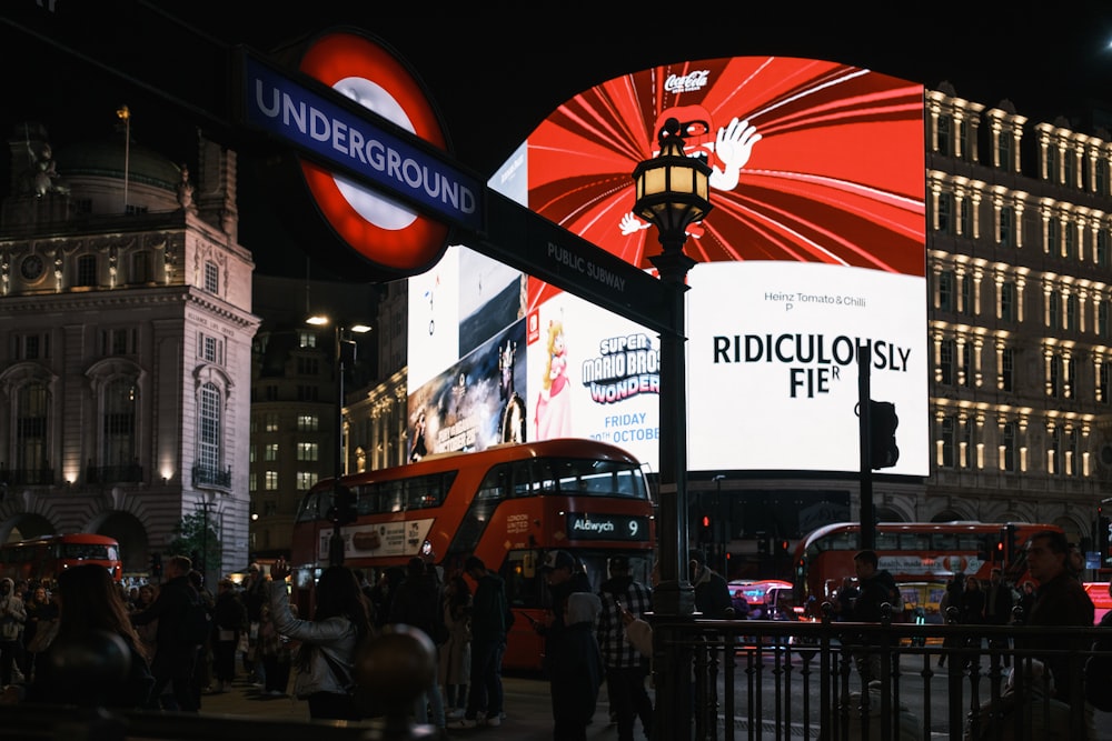 a crowd of people walking around a city at night