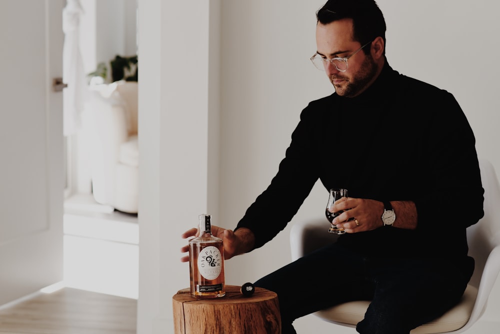 a man sitting on a stool holding a glass of wine