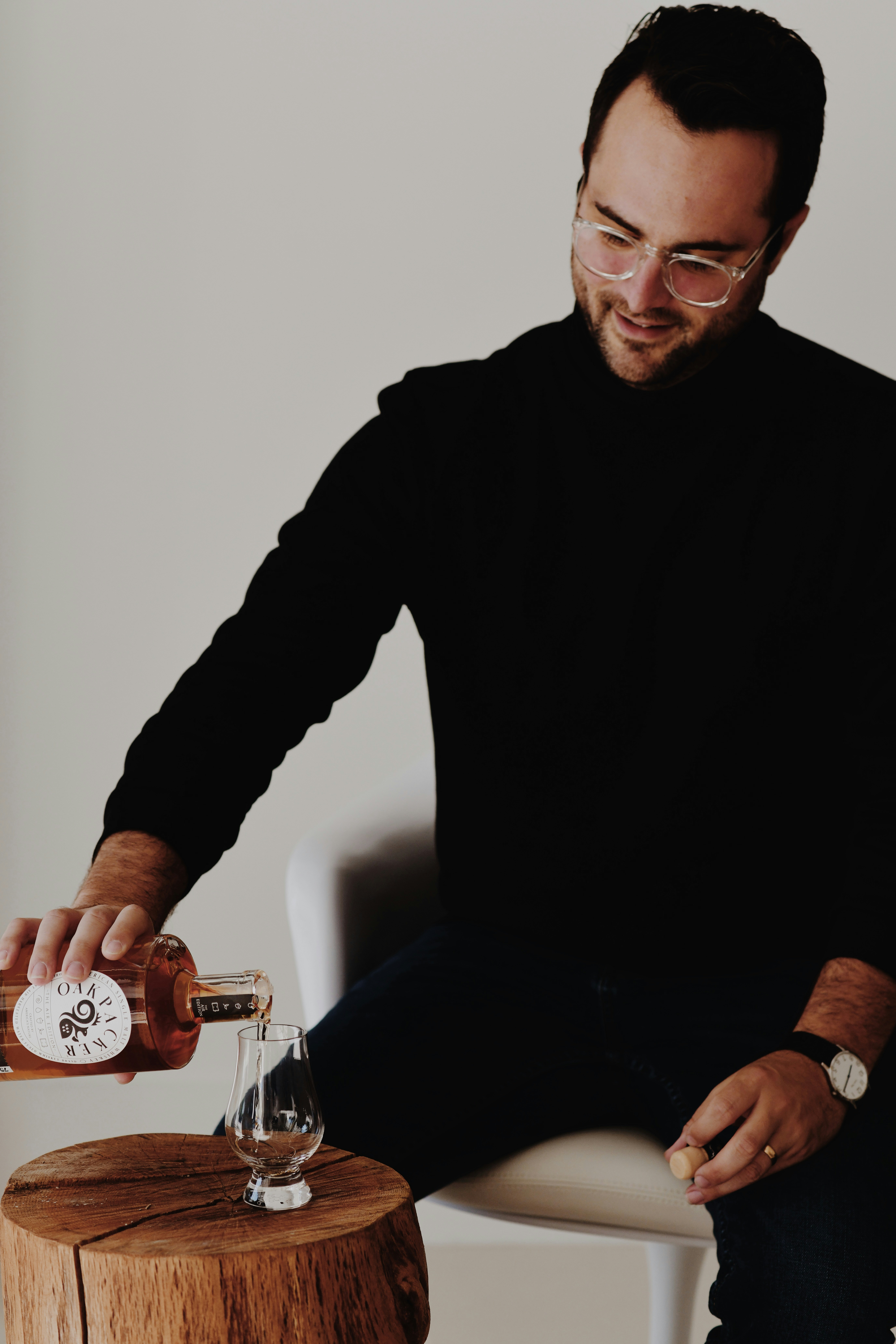 a man sitting in a chair pouring a glass of wine