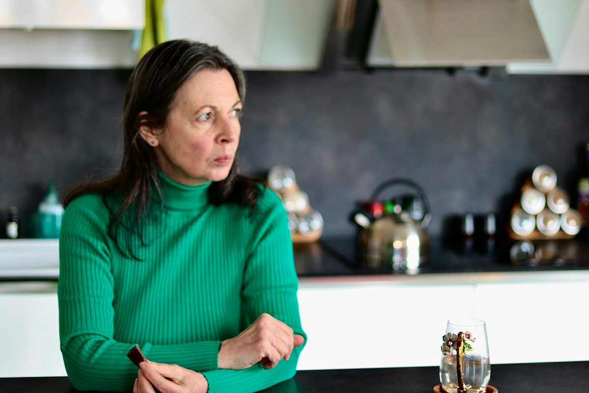 Worried woman sitting at a kitchen table, wondering why do I feel anxious when someone is mad at me