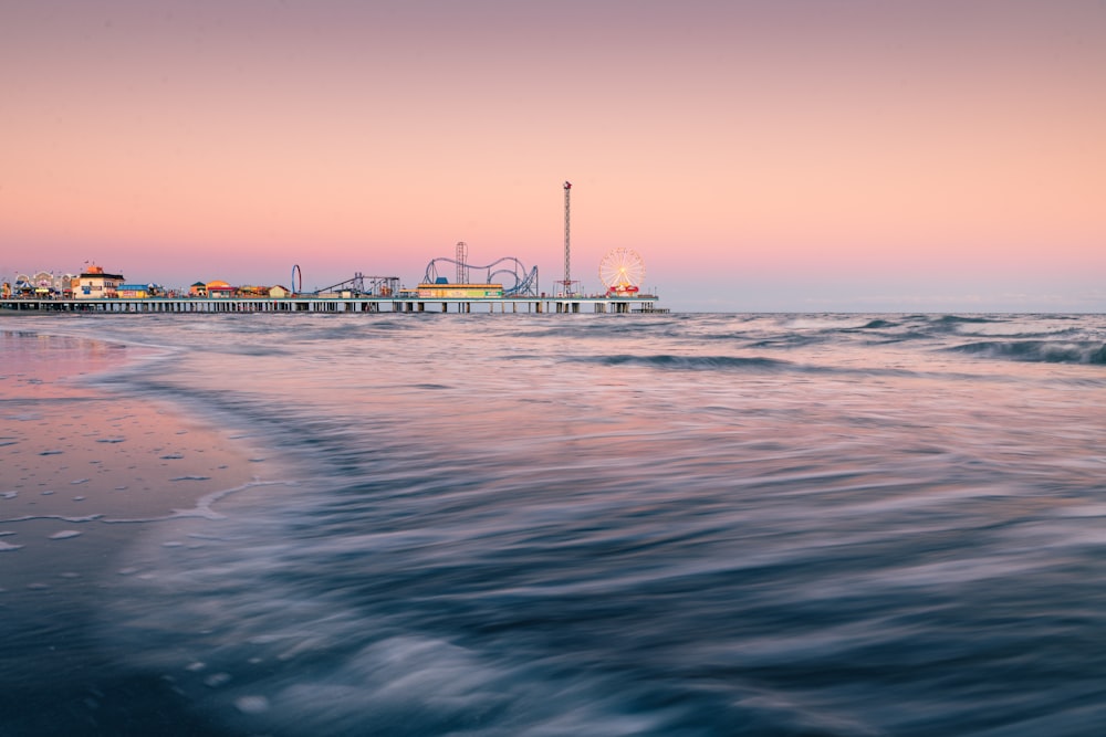 a pier on a beach with waves in the foreground