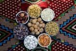 A vibrant bowl filled with assorted dry fruit laddus against a bright backdrop.