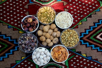 A close-up of assorted colorful dry fruits arranged in traditional Indian brass bowls.