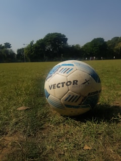 A soccer ball on a grassy field under a clear blue sky.