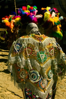 A vibrant carnival costume with colorful feathers and intricate beadwork displayed on a mannequin.