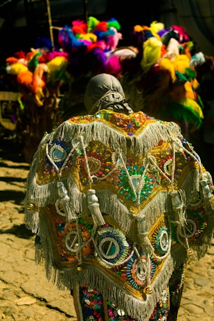 A vibrant carnival costume with colorful feathers and intricate beadwork displayed on a mannequin.