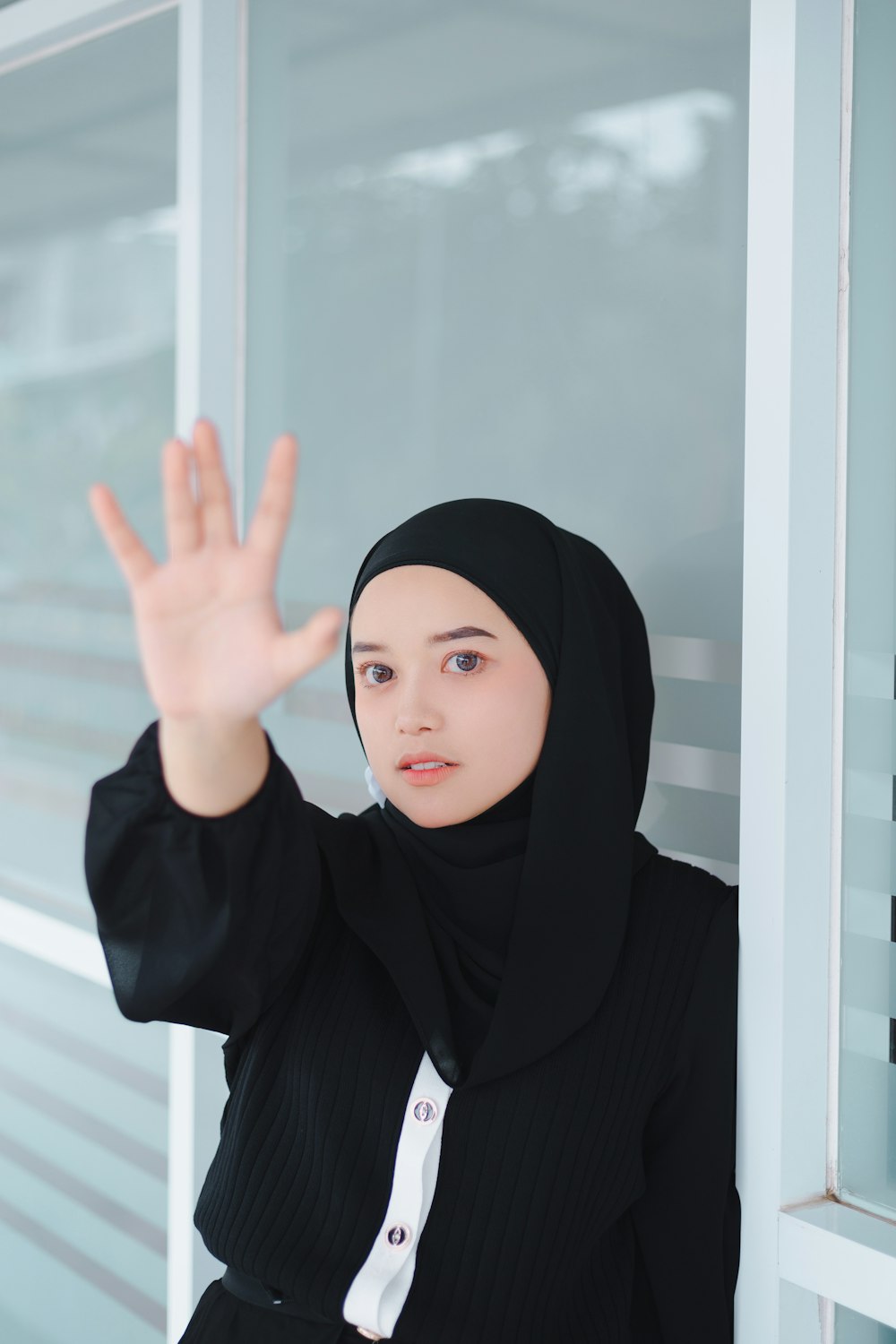a woman in a black hijab is holding her hand up