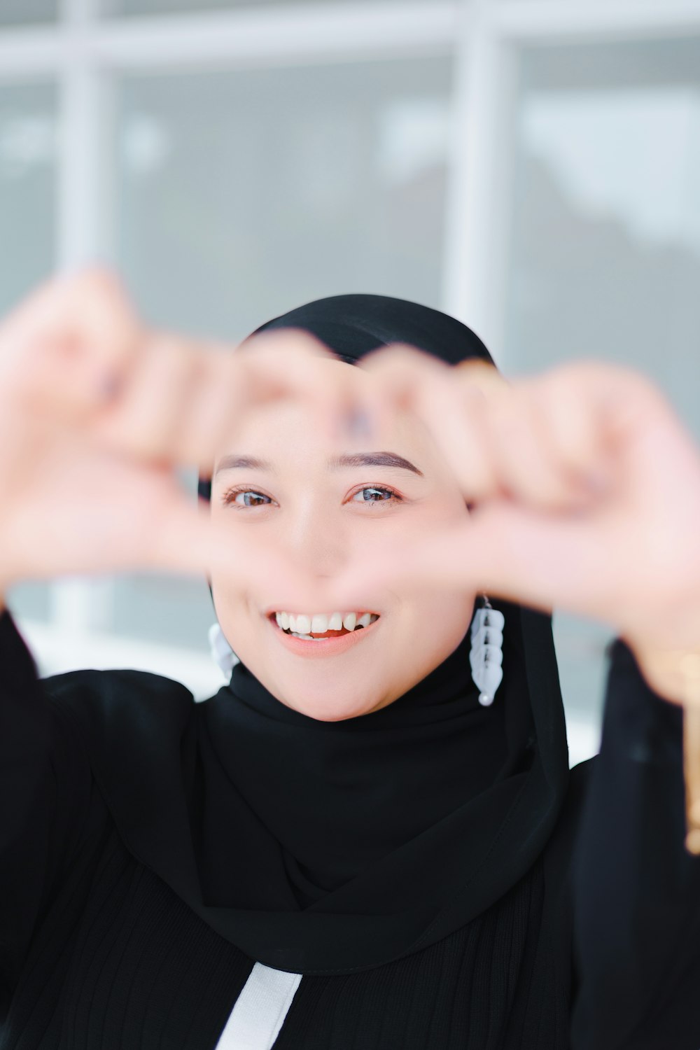 a woman wearing a black hijab making a frame with her hands