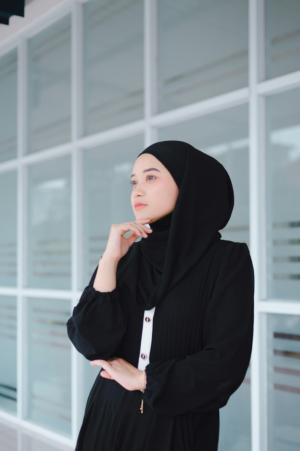 a woman wearing a black hijab standing in front of a building