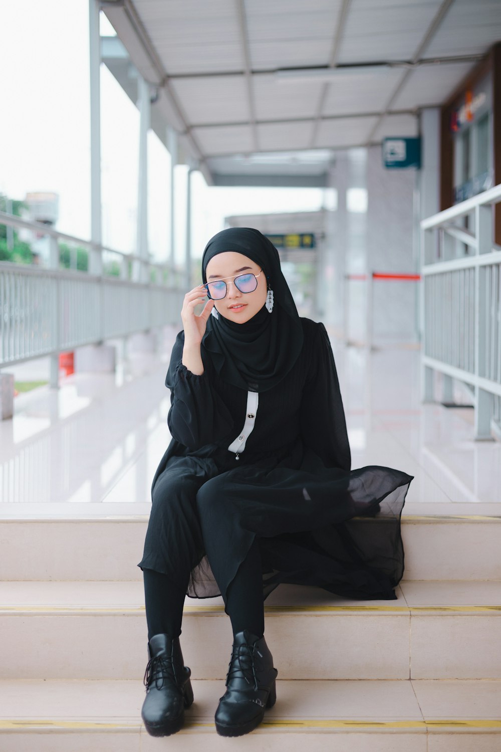 a woman in a black hijab is sitting on some steps