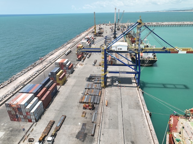 A vibrant photo of a shipping container by the sea with crates of fresh turmeric, honey jars, and cashew nuts ready for export.
