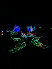 Colorful 3D-printed flower pots glowing under neon lights on a futuristic display stand