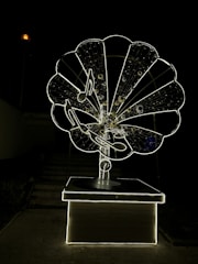 A large, intricately designed structure resembling an old-fashioned gramophone, illuminated against a dark background. The gramophone features musical notes and a glowing outline, creating a striking visual effect.
