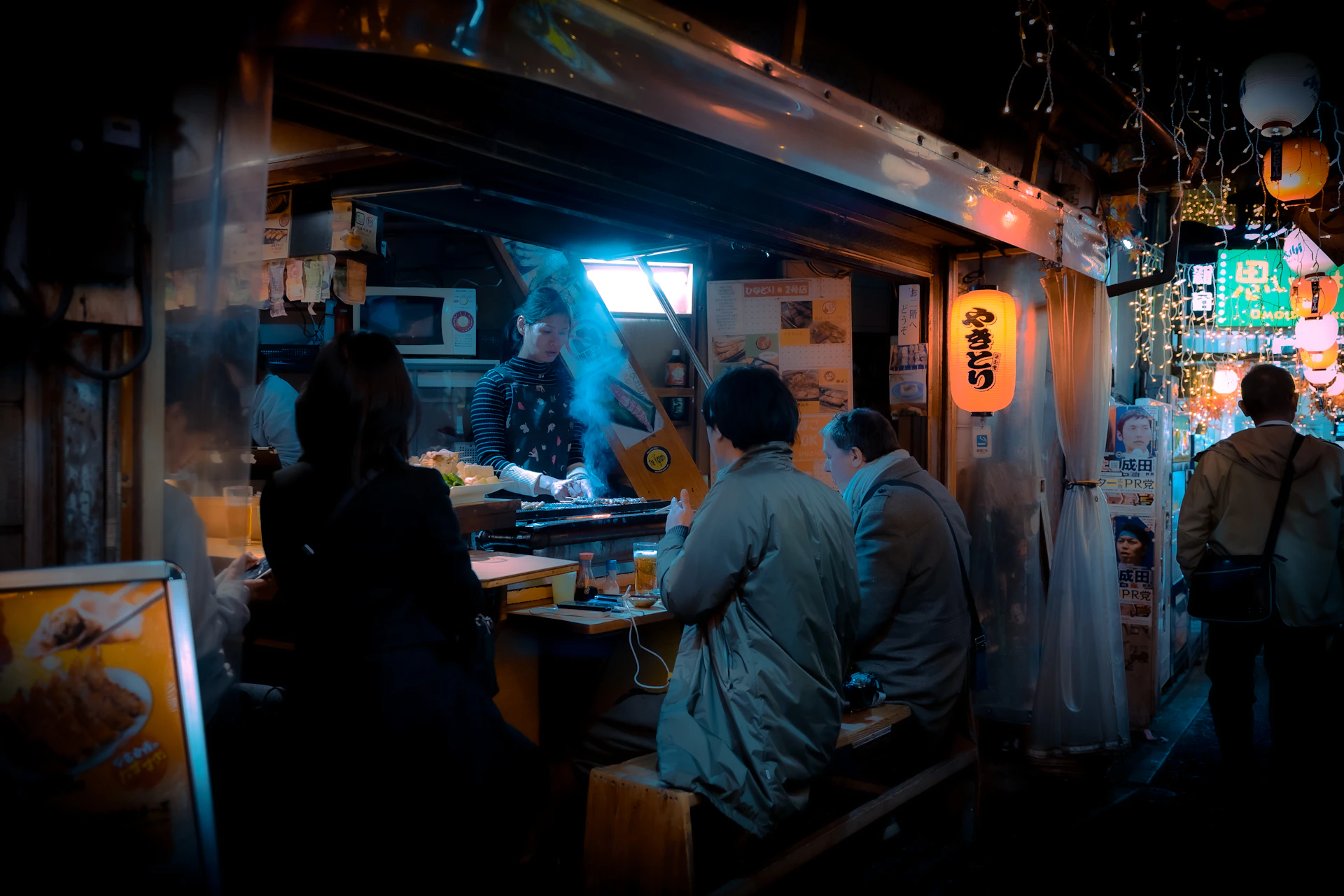 A lively scene of friends sharing laughter and plates of assorted yakitori, capturing the friendly atmosphere of the restaurant.