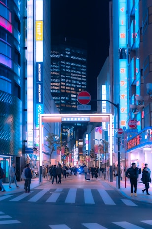 A bustling city street at night illuminated by vibrant neon lights and lively crowds.