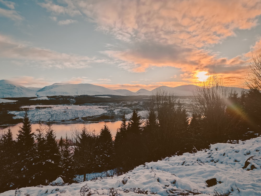 the sun is setting over a snowy landscape