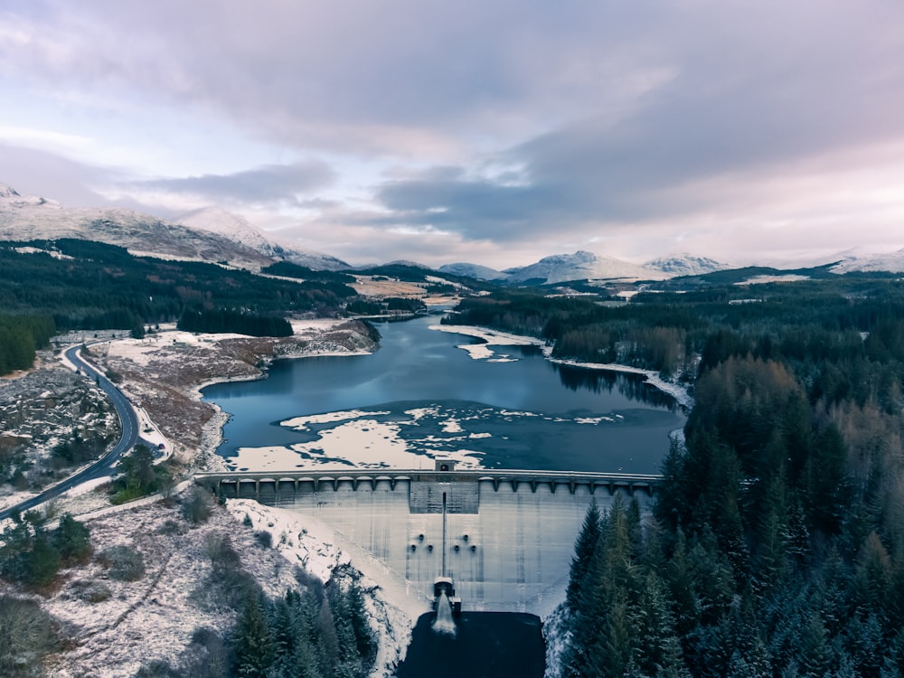 a large dam surrounded by snow covered mountains