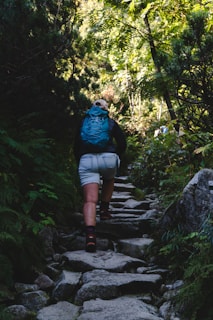 Close-up of a backpacker tying hiking boots on a forest trail surrounded by lush greenery.