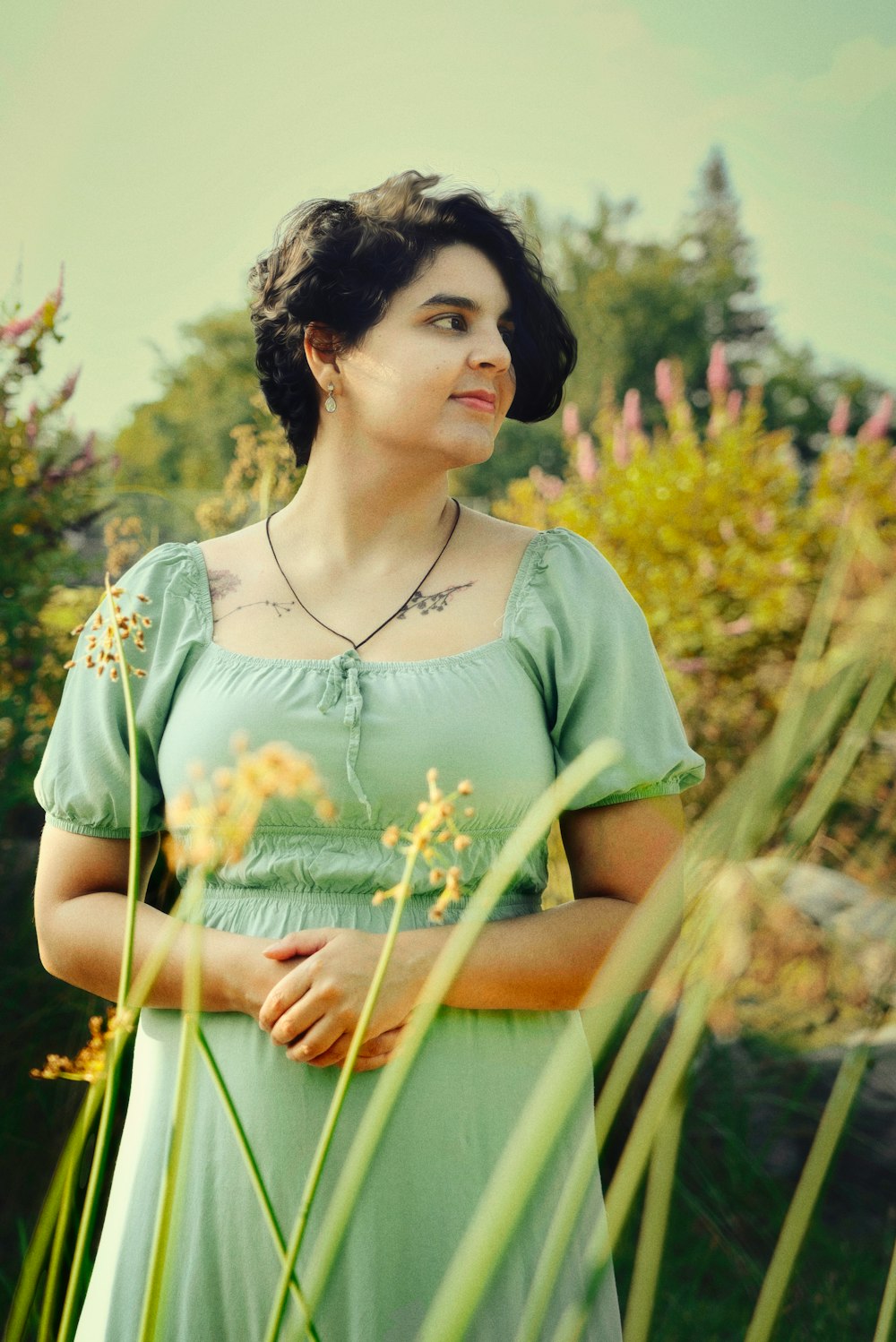 a woman in a green dress standing in a field