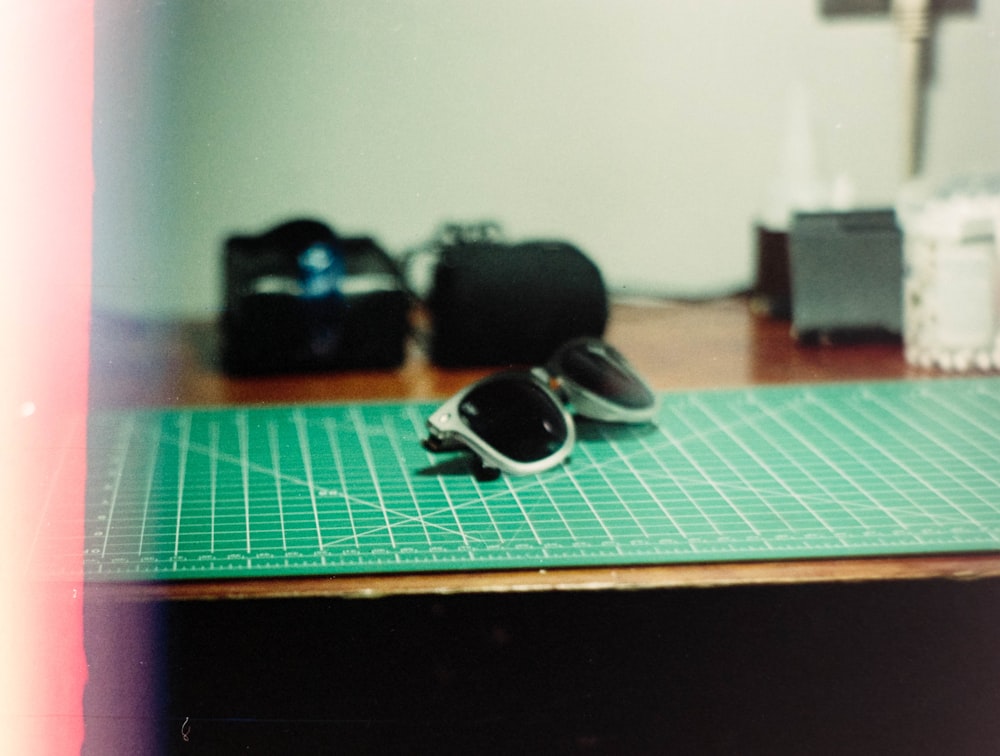 a pair of sunglasses sitting on top of a cutting mat