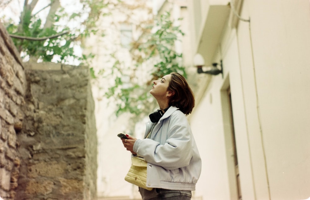 a woman standing in an alley holding a cell phone