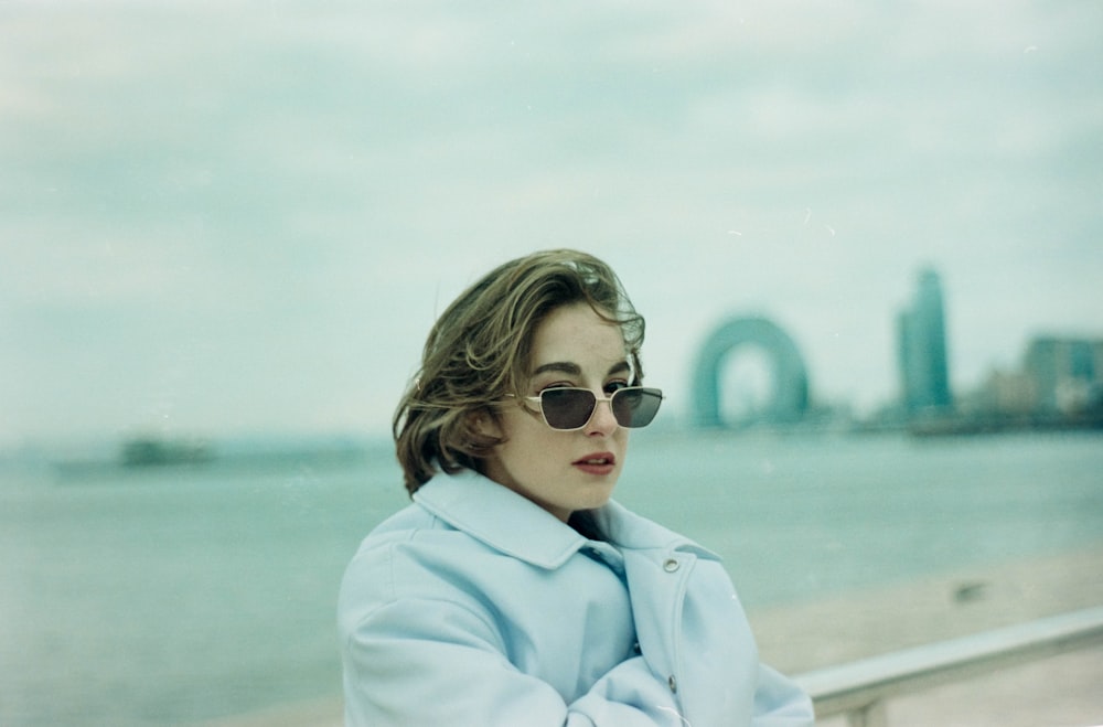 a woman in a blue coat and sunglasses