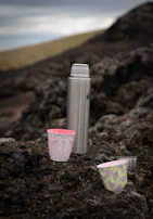 A colorful lineup of Frostara tumblers on a picnic blanket in a park.