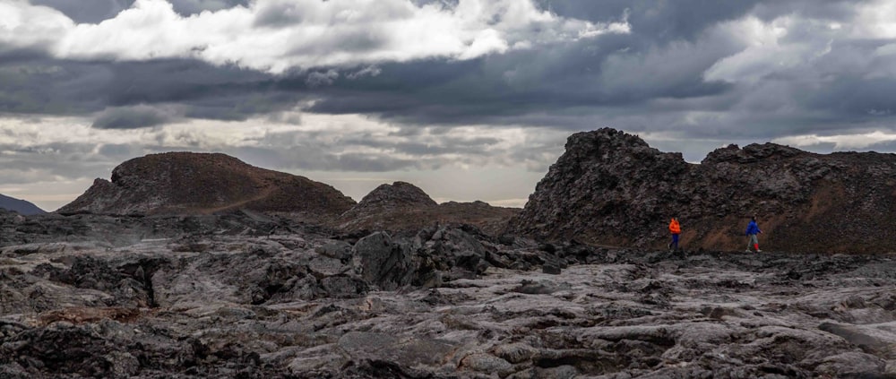 a couple of people standing on top of a rocky field