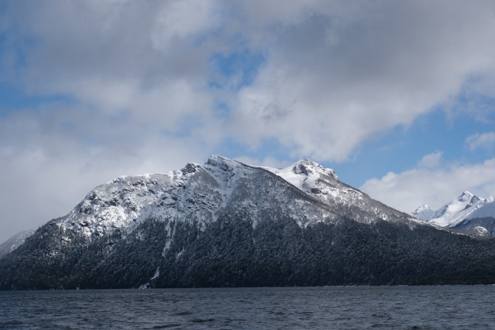 a mountain covered in snow next to a body of water