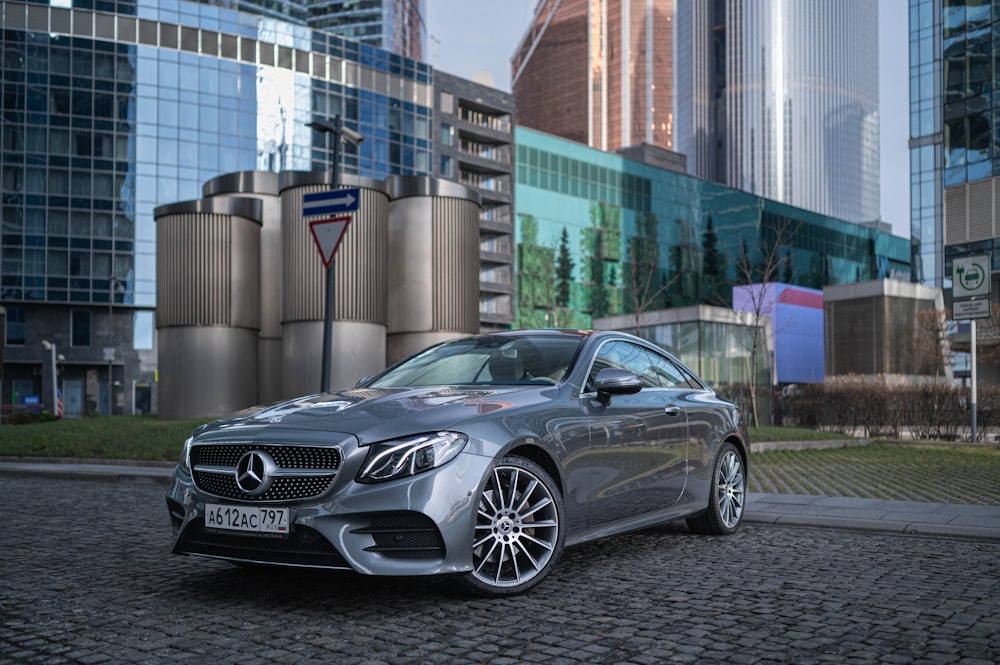 a silver car parked in front of a tall building